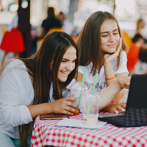 Two girls sitting in an outdoor café working on strategic profiling and student branding with student profile pro services.